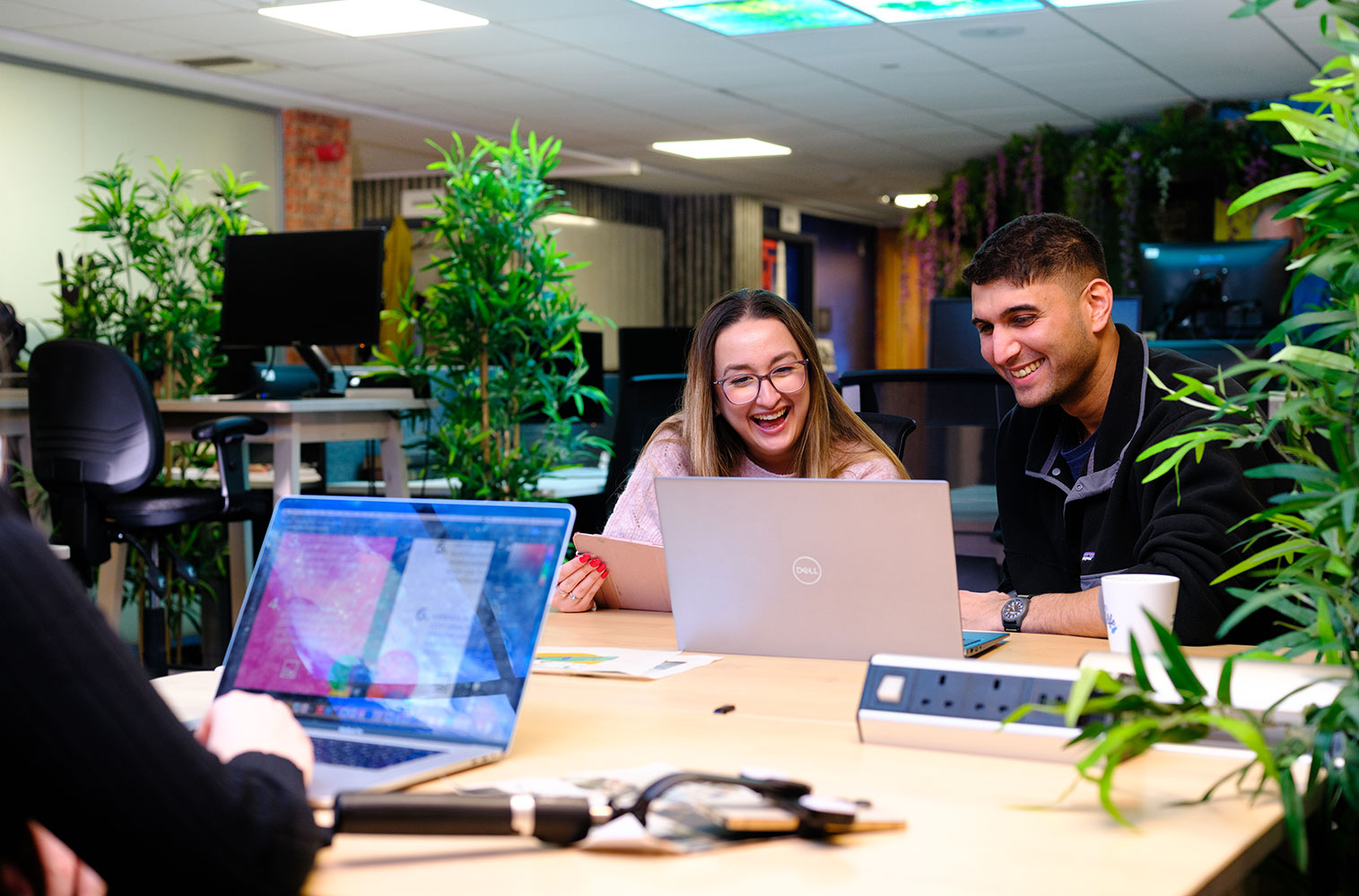 2 cobolt team members laughing and smiling at the same laptop