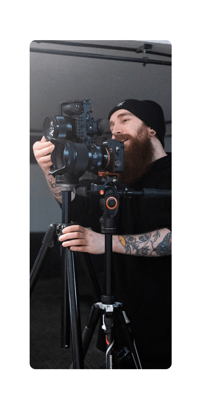 photographer standing behind camera looking down lens